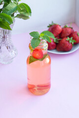 Homemade strawberry mint lemonade in two glass bottles to go. Eco packaging, reusable dishes zero waste concept. Natural healthy alcohol free drink recipe for hot summer on pink background