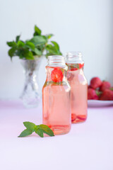 Homemade strawberry mint lemonade in two glass bottles to go. Eco packaging, reusable dishes zero waste concept. Natural healthy alcohol free drink recipe for hot summer on pink background