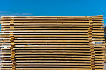 Wooden boards for construction stacked outdoors under a bare sky, horizontally, building material