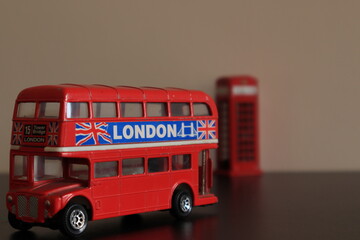 Miniature double decker vintage bus toy with an English classical cabin at background.