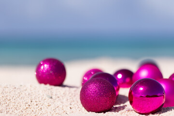 Pink Christmas balls on the sand. Christmas in the tropics. Selective focus