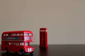 Foto op Plexiglas Miniatuur dubbeldekker vintage bus speelgoed met een Engelse klassieke cabine op de achtergrond. © JP CARNEVALLI