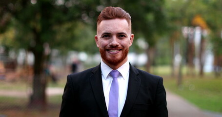 Man wearing suit standing outside at park, irish ginger executive person outdoors