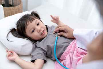 The doctor is using a stethoscope Listen to heart rate Of a 3 year old  girl patient which lying on...