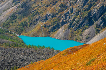 Turquoise lake in the caldera. Deep mountain lake of blue color among high mountains with sunny weather. Wonderful bright view to deep blue mountain lake among sunlit autumn rocks.