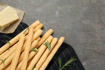 Delicious grissini with rosemary and cheese on grey table, flat lay. Space for text