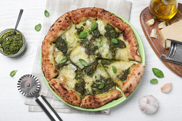 Delicious pizza with pesto, cheese and basil served on white wooden table, flat lay