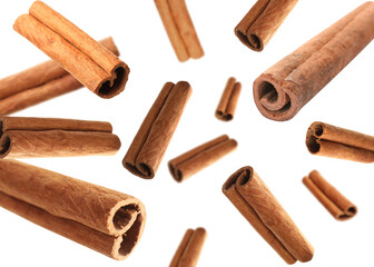 Aromatic cinnamon sticks falling on white background