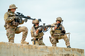 Fototapeta premium Military or soldier team with gun stay on concrete wall and prepare for battle with enemy in field with day light.