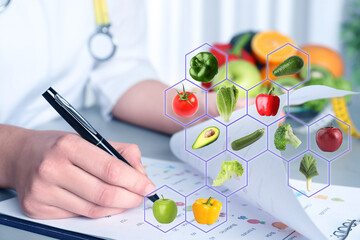 Nutritionist working at table in office and images of different vegetables and fruits. Healthy eating
