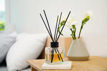 Foto op Canvas Reed diffuser and vase with bouquet on wooden nightstand in bedroom © New Africa