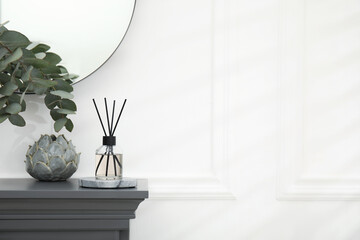 Reed diffuser and home decor on grey table near white wall. Space for text - obrazy, fototapety, plakaty