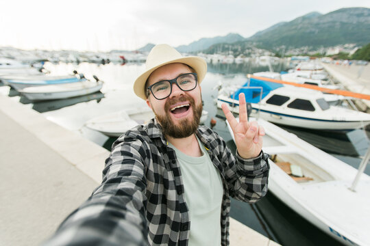 Traveller man taking selfie of luxury yachts marine during sunny day - travel and summer concept