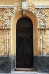 Fototapeta na wymiar Entrance of house with arched wooden door and beautiful moldings