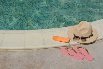 Different beach accessories near outdoor swimming pool on sunny day, space for text