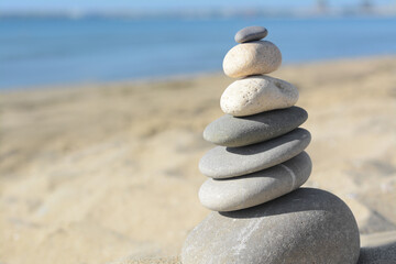 Fototapeta na wymiar Stack of stones on sandy beach, closeup. Space for text