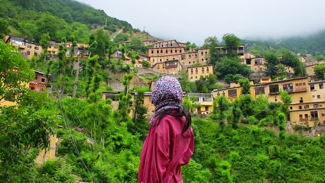 Tourist woman stand enjoy scenic Masuleh village panorama in north east Iran - popular famous tourism destination in persia