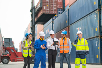 Group of professional engineer, worker or technician walk and discuss together about work in cargo container workplace area with crane and stack of container tank on background.