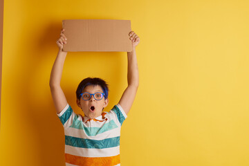 a boy with glasses on a yellow background with different emotions, holds a cardboard banner with empty space for text