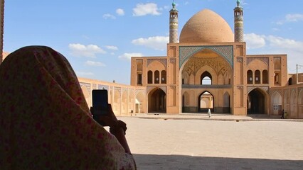 Kashan, Iran - 29th may, 2022: tourist stand take photo of famous beautiful historical landmark Agha Bozorg Mosque in Kashan city