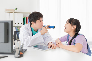 Obraz premium asian doctor use flashlight and diagnosis children patient in hospital, children open her mount and show her tongue, child clinical screening, happiness hospital