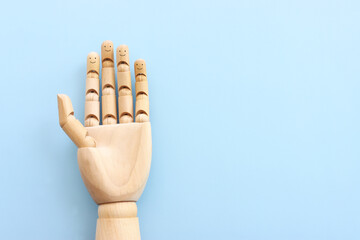 Wooden figure hand with happy faces on blue background.