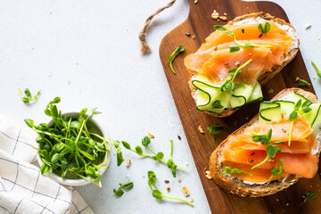 Open sandwich with cream cheese, salmon and cucumber. Top view at white table.