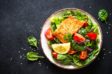 Green salad with salmon fillet. Healthy lunch, diet nutrition. Top view on black.