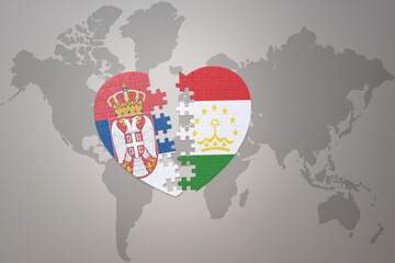 puzzle heart with the national flag of tajikistan and serbia on a world map background.Concept.