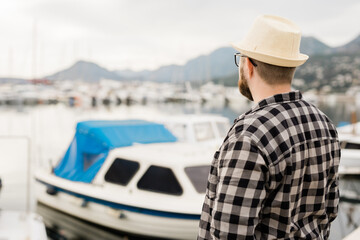 Rear view man wearing hat with yachts and marina background with copy space and empty place for advertising