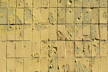 Texture of old tile wall. Yellow paint crumbled. Paint on top of tiles.