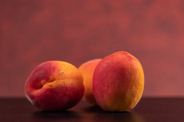 Fototapeta na wymiar Fresh apricots on black table with red background