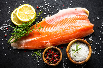 Fresh fish. Salmon fish, fresh raw fillet at black background. Top view with ingredients for cooking.