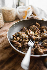fried homemade liver in a pan with a fork in the kitchen (selective focus, blurred background)