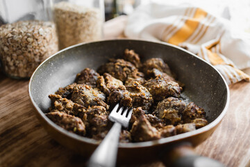 fried homemade liver in a pan with a fork in the kitchen (selective focus, blurred background)