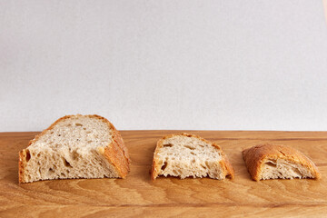 Three pieces of bread larger, smaller and even smaller on a wooden board. The concept of the food crisis of 2022 and 2023.