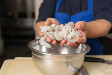 Hands of a cooker with a raw of seafood to prepare ceviche in a restaurant