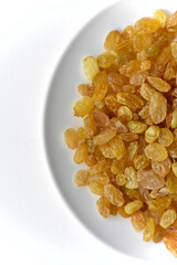 Yellow juicy raisins on a white plate