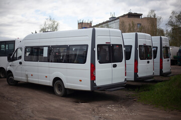 Minibuses in parking lot. Transport at bus station. Cars are white.