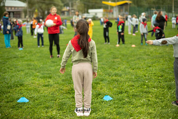 Child does exercises in fresh air. Sports activity for schoolchildren. Children on green grass....