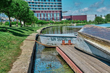 Fototapeta premium Blue boat stands on the anchor near the shore in the parking lot tied whith a chain