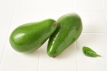 Two fresh whole avocado on a white table. Selective focus
