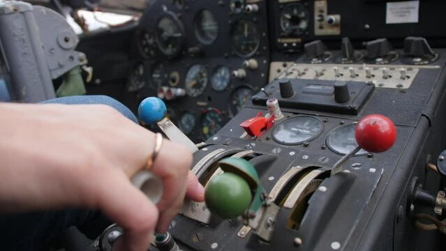 A close-up of a pilot's hand with a wedding ring grasping the thrust lever on an old instrument panel of an An-2 aircraft.