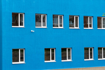 Fototapeta na wymiar the wall of a new blue house with windows and a surveillance camera. 
