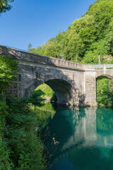 Fototapeta na wymiar Turquise water in Soca river with old stone bridge in Most Na Soci town,Slovenia.