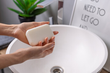 hand holding soap near sink with water