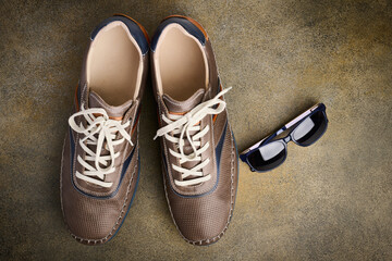 Mens leather sports shoes and sunglasses, top view, flat lay