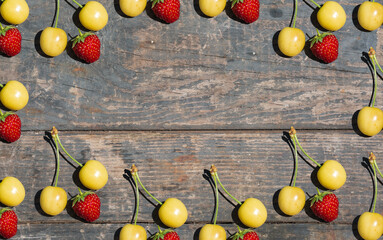 yellow cherry and red strawberry on wooden texture. boards. Rural, gardening, vegetable garden, fruits