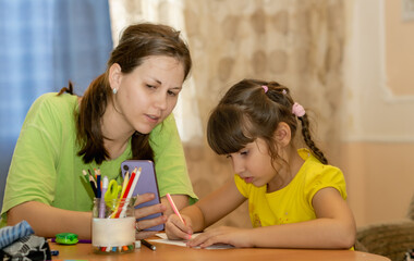 young mother with her daughter helping her with homework