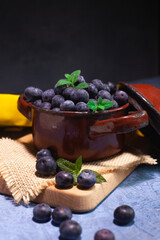 deliciosos arándanos frescos en un recipiente de metal con hojas verdes frescas